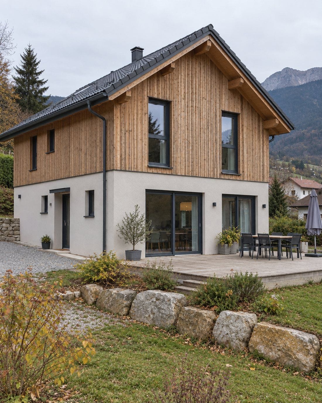 Maison individuelle neuve à ossature bois et enduit clair, terrasse et jardin aménagés, montagnes en arrière-plan